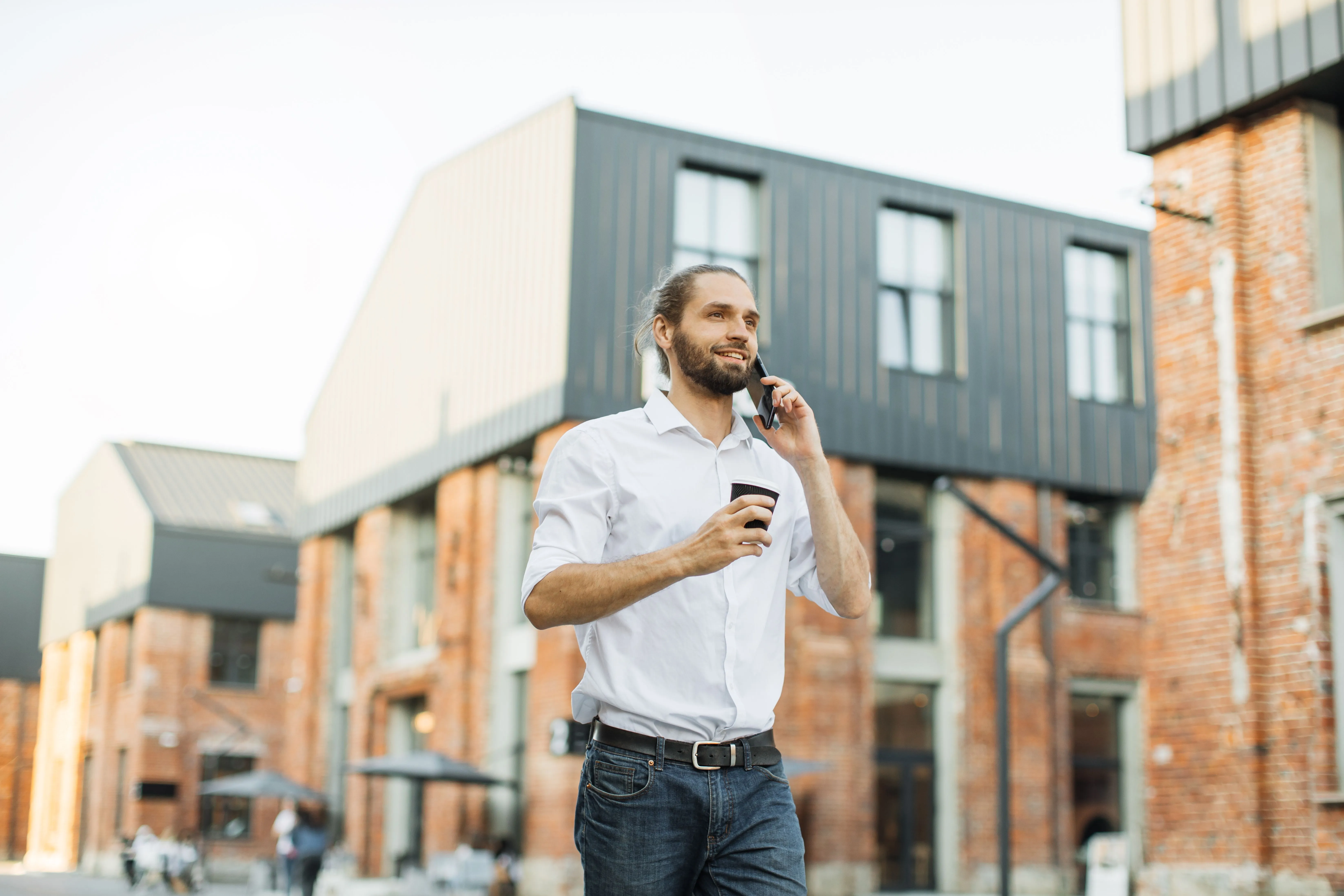 Przedsiębiorca rozmawiający przez telefon przed budynkiem mieszkalnym - klient pożyczki pod zastaw nieruchomości Horyzont Capital
